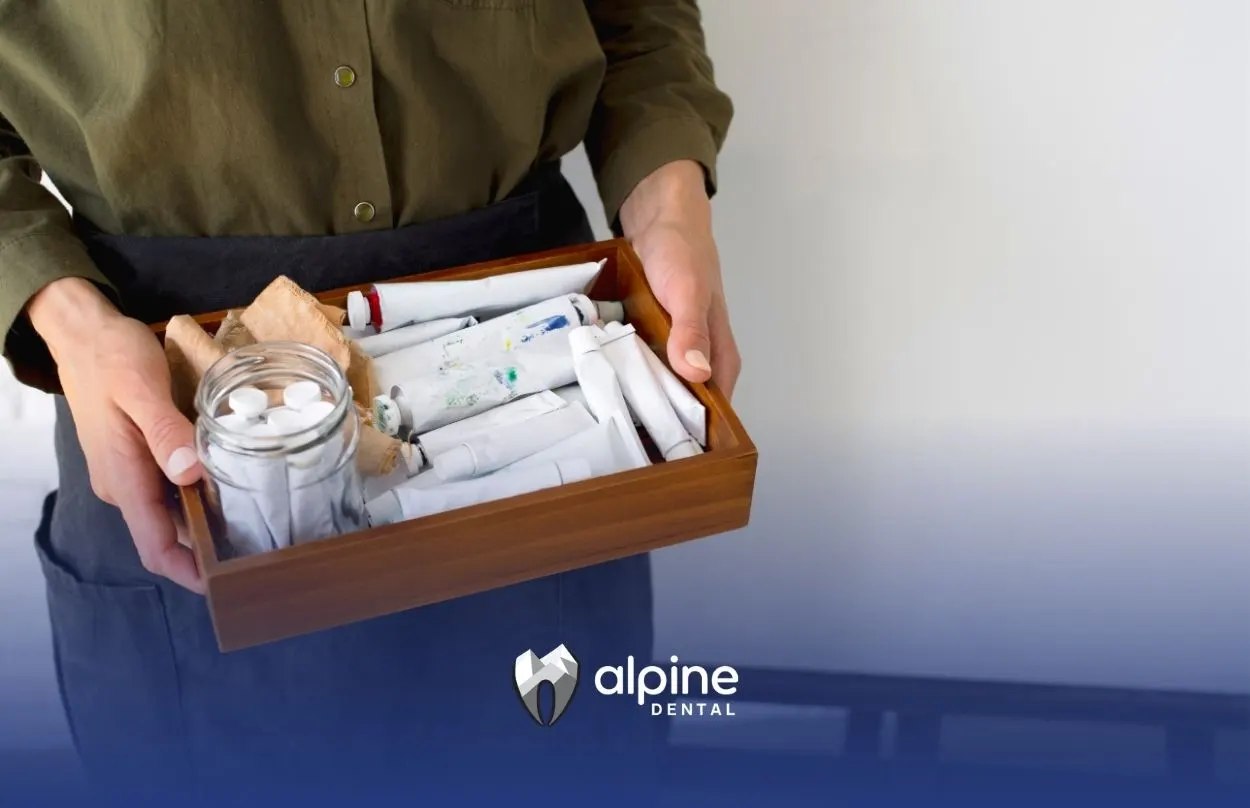 Person holding a wooden tray filled with dental supplies and essentials for creating a home dental emergency kit.