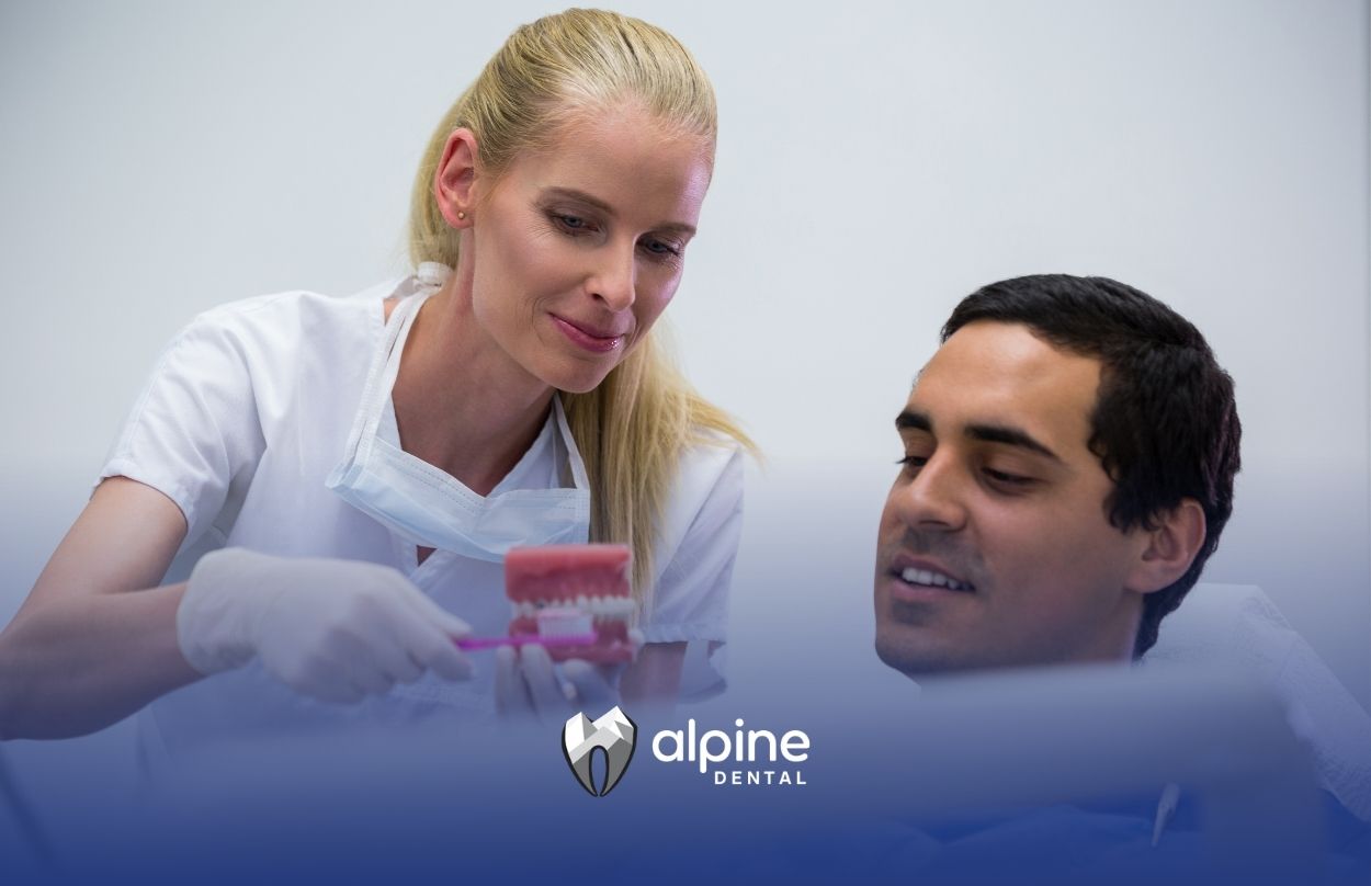 Dentist explaining dentures to a patient while demonstrating a dental model during a consultation in a modern clinic.