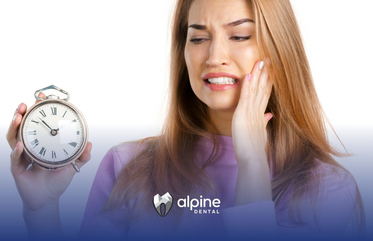 Woman experiencing tooth pain while holding a clock to represent urgent dental care needed after a knocked out tooth.