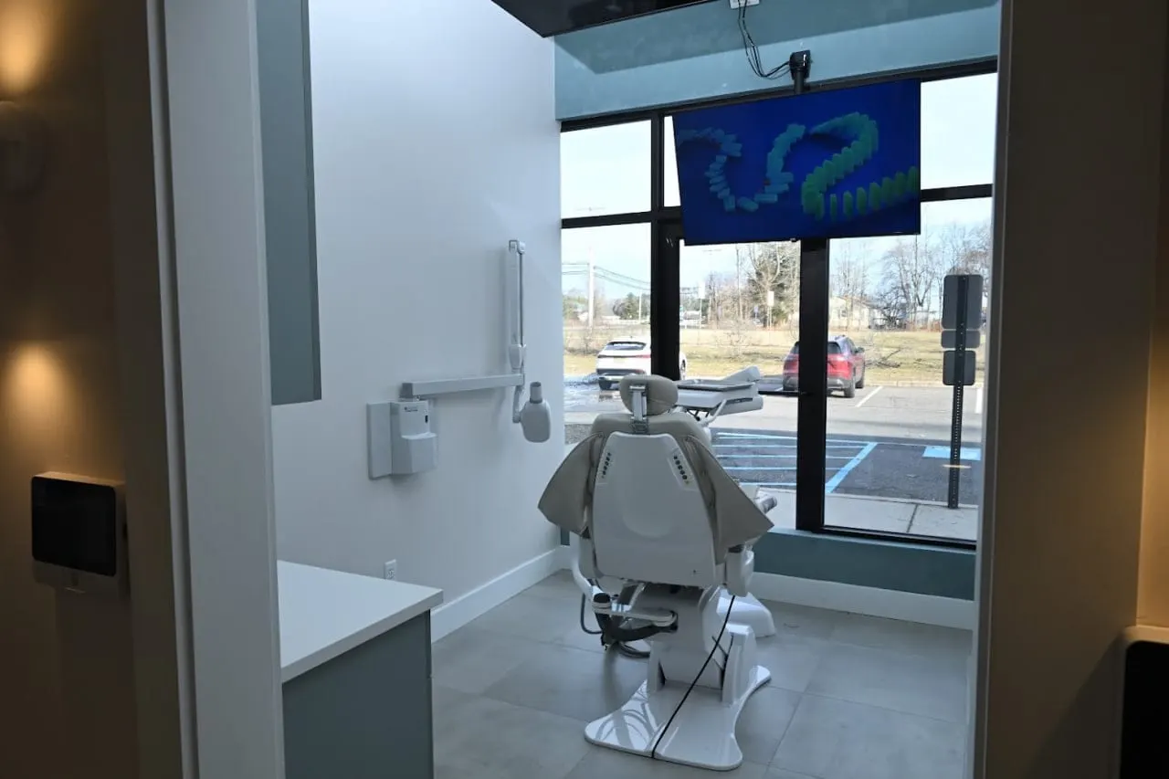 Bright treatment room with a dental chair, ceiling TV and street-facing windows at Alpine Dental in Jackson