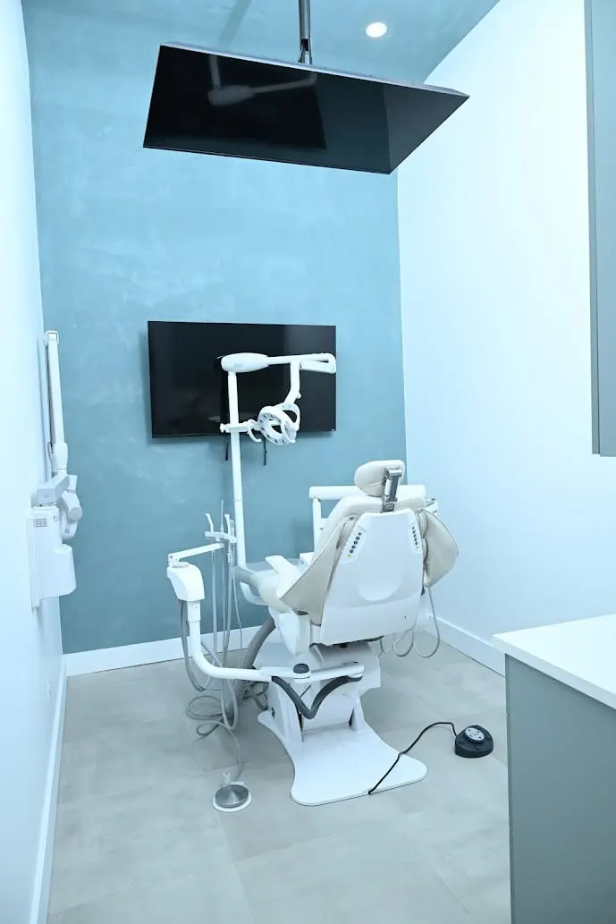 Treatment room with a dental chair, overhead TV and blue feature wall at Alpine Dental in Jackson